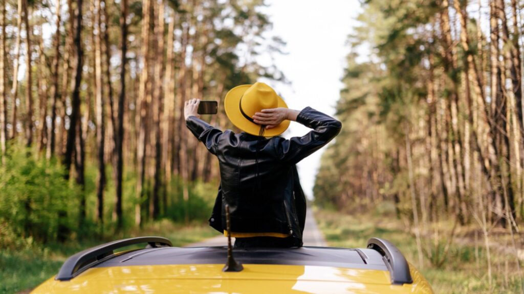 Woman taking picture through sunroof of car