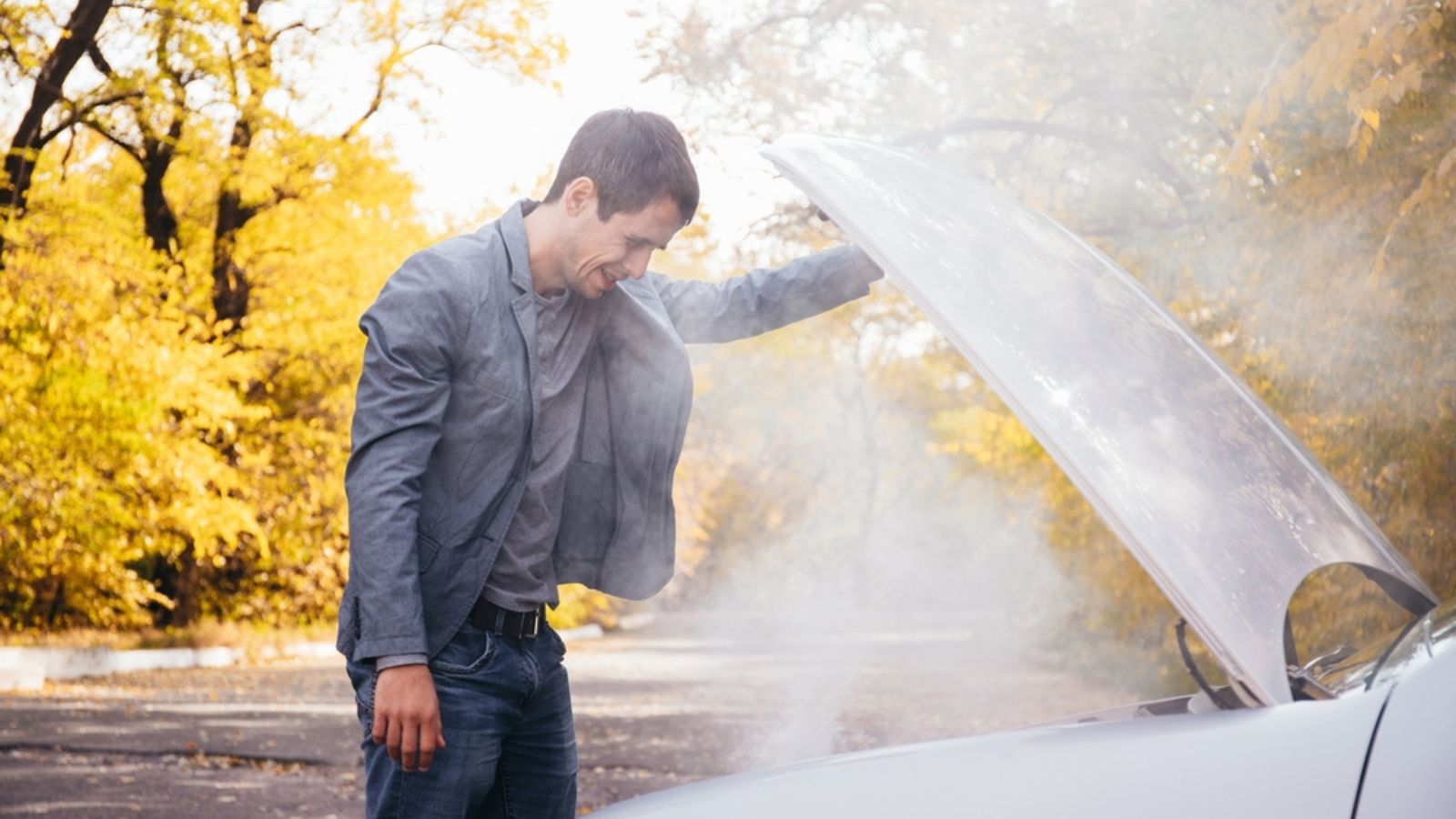 A man looks under the open hood of a car