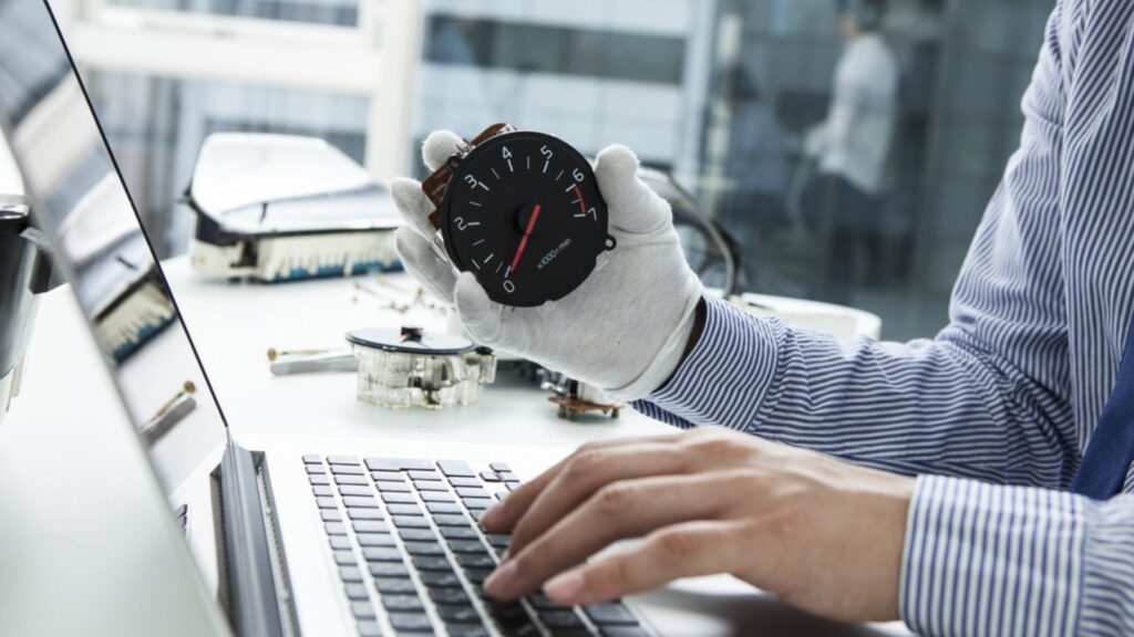 Close-up of mechanic fixing car meter record on laptop at the office