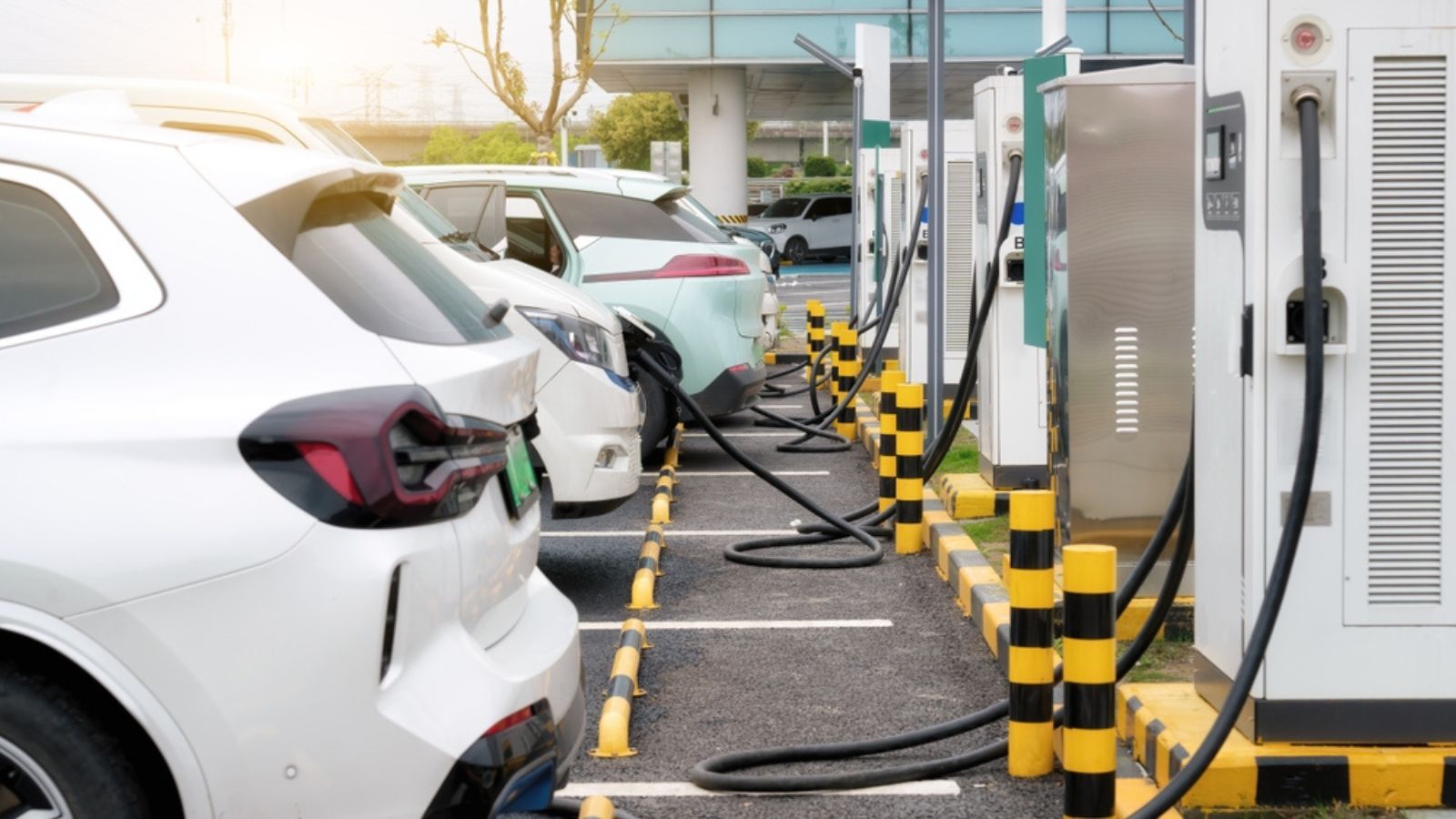 A car at an EV charging station with cables and charging bays lined up for multiple drivers.
