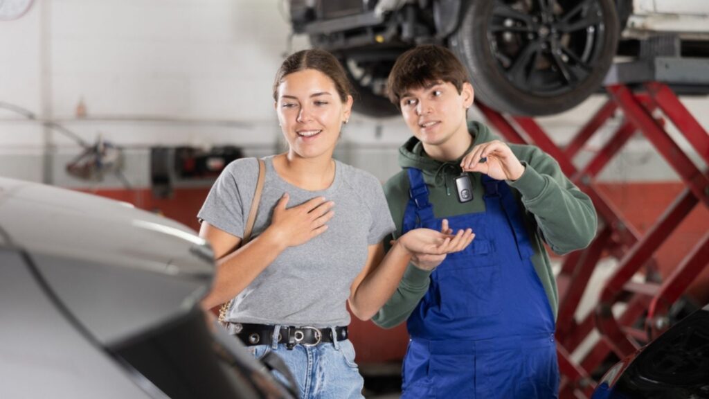 happy mechanic giving back car key to female client