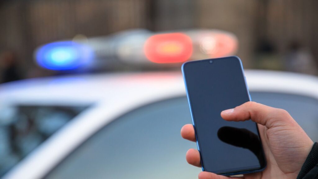 man holding phone with police car light