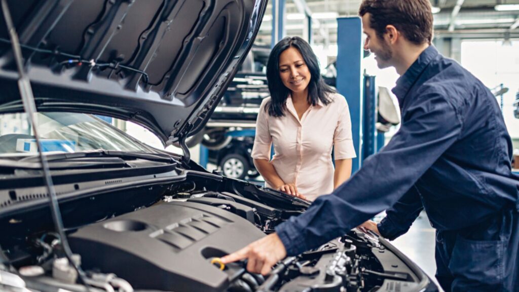 mechanic gesturing at engine to female client