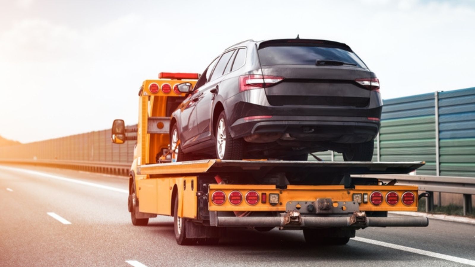 side view of the flatbed tow truck with a damaged vehicle