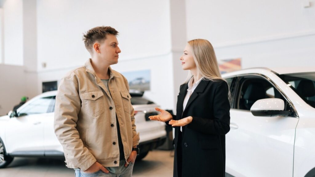 young man customer talking to woman car dealer