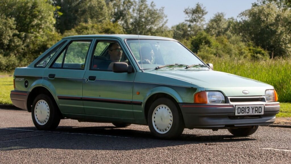 1987 green Ford Escort classic car driving on a British country road