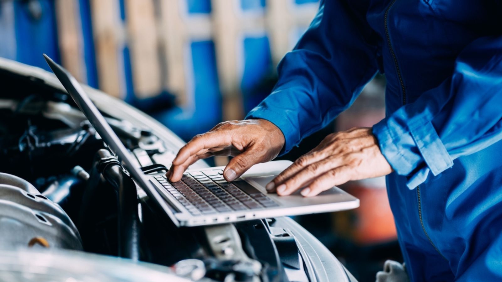 Automotive mechanic repairman using laptop computer and checking engine in the engine room