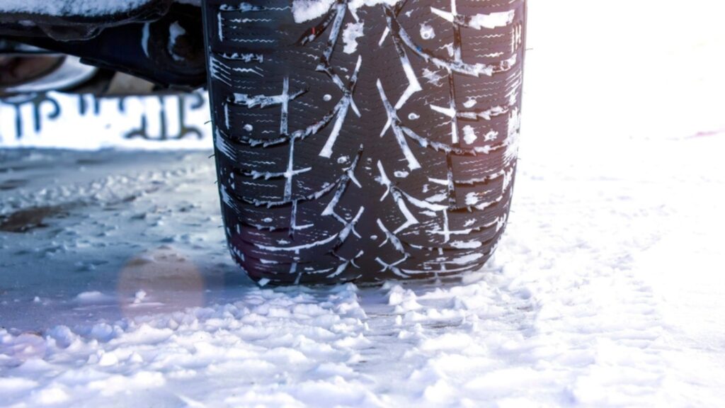Driving car with winter tire wheel on snow road