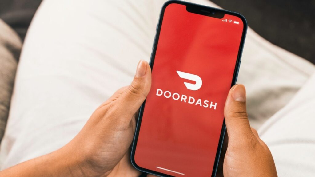 Female hand holding a smartphone with Doordash online food ordering and delivery platform app