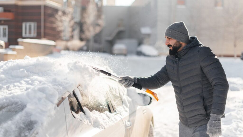 Man cleaning snow from his car