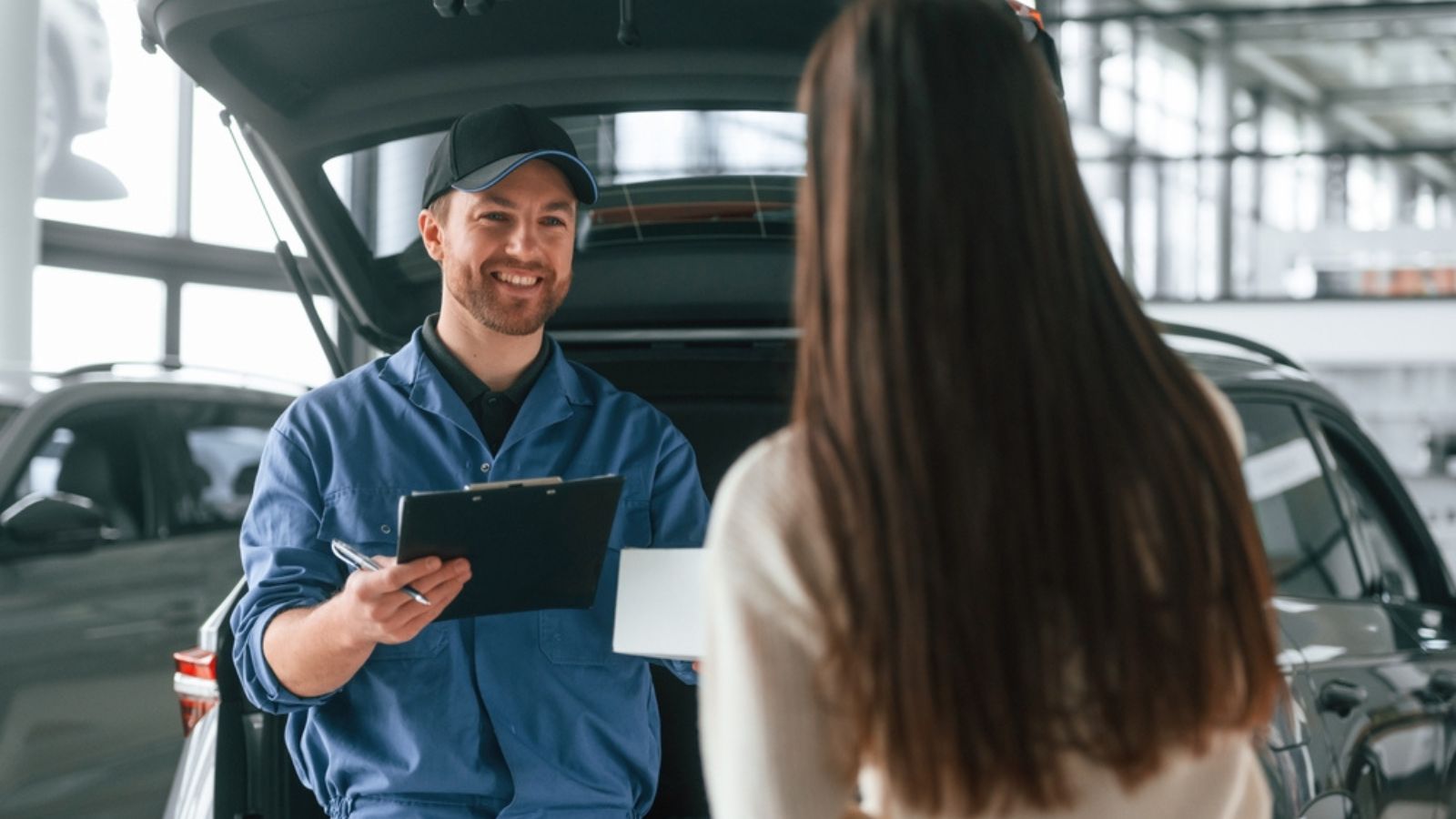 Young woman is visiting auto mechanic in garage