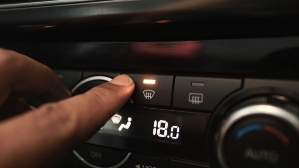 hand pressing the defogger button to remove the fog on the windshield