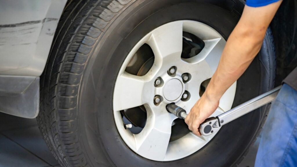 Auto mechanic using Torque wrench to inspection the wheel nuts for safety in travel in mechanics garage