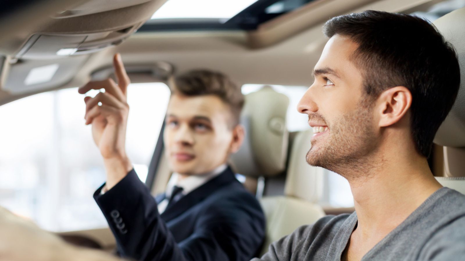 Handsome young salesman showing all the car features to the customer