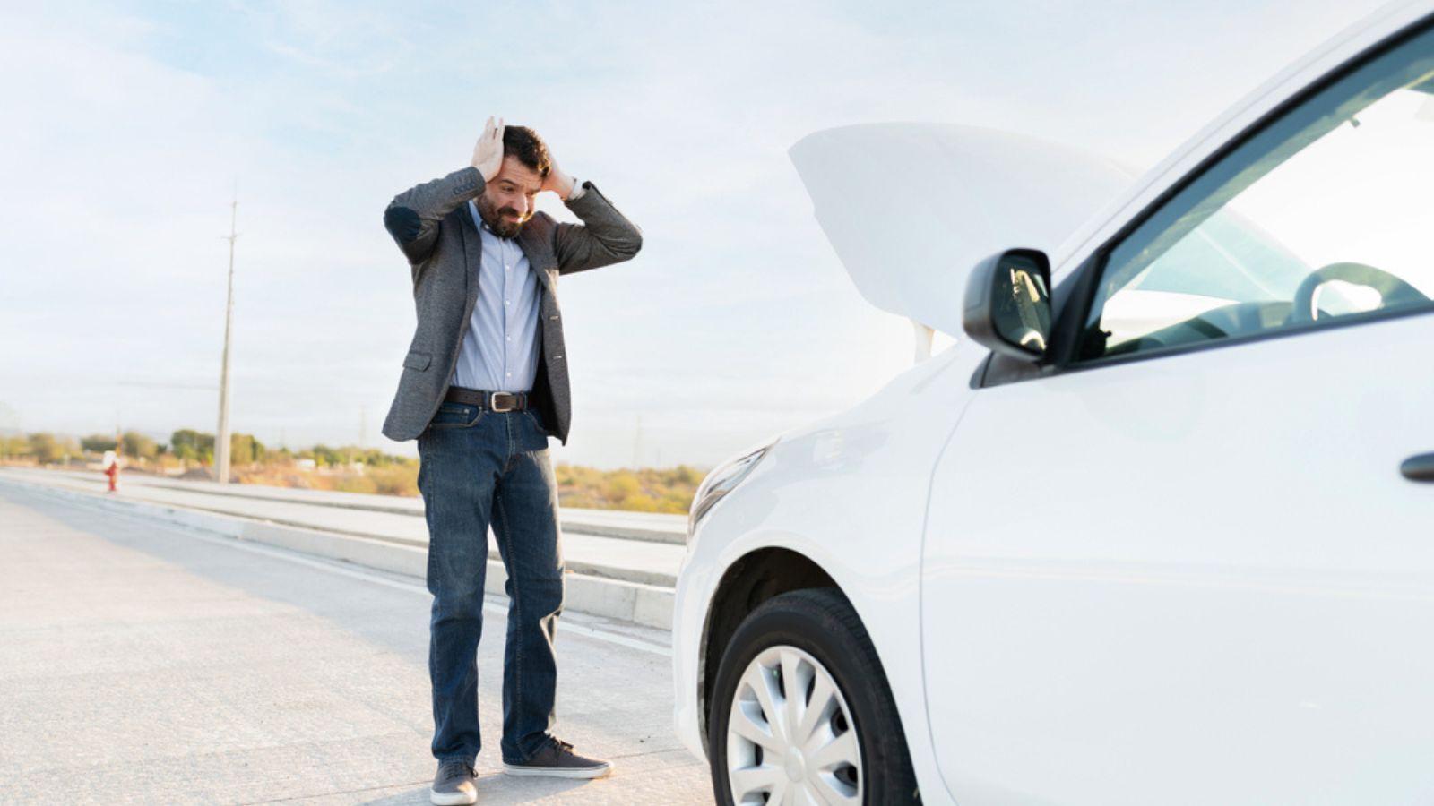 Hispanic adult man looking angry and worried because his car broke down in the middle of the highway