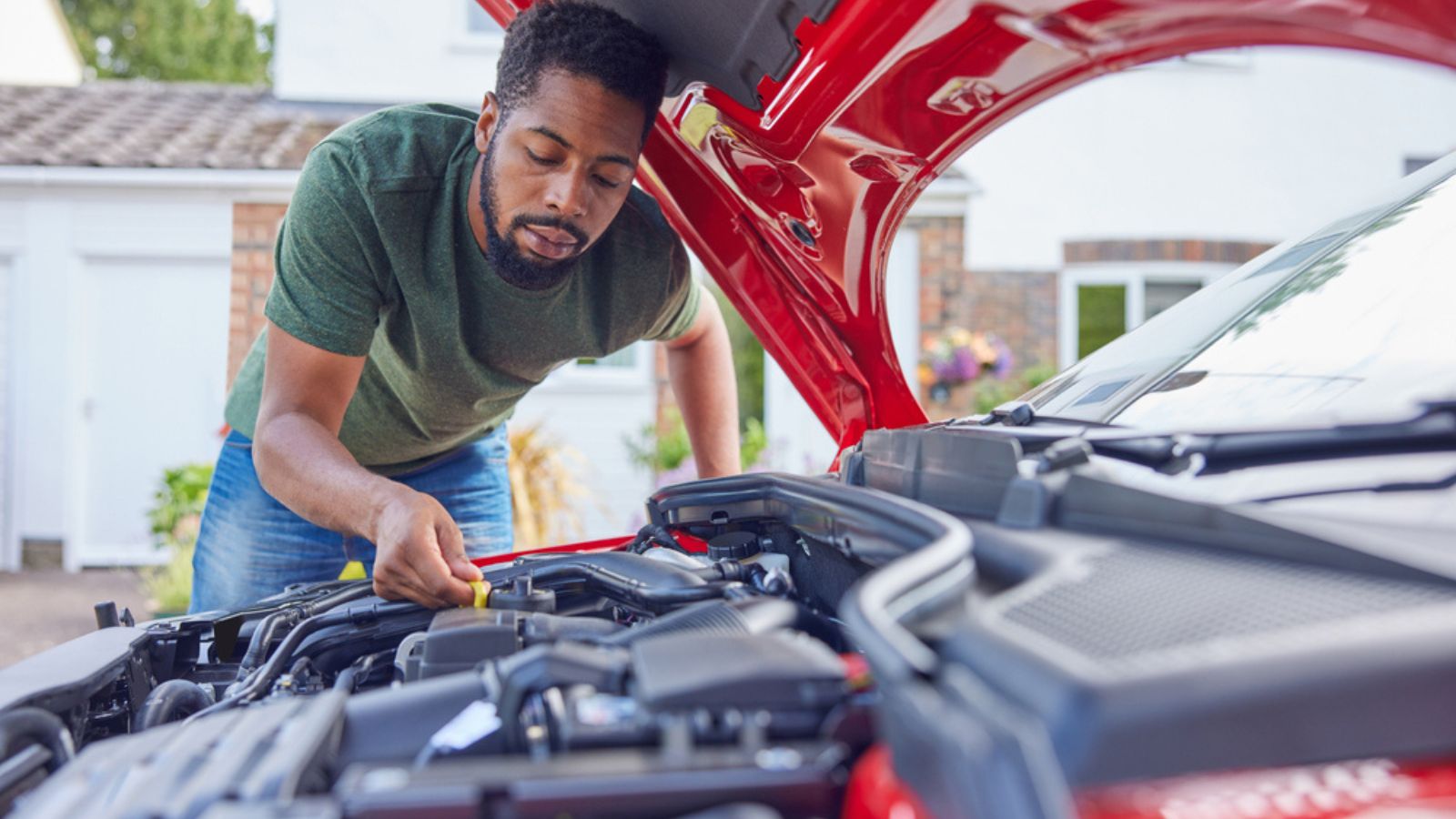 Man Working Under Hood Checking Car Engine Oil Level On Dipstick