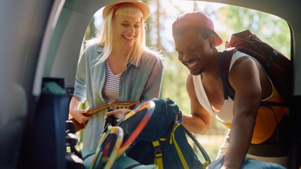 Young happy couple packing luggage in their camping van
