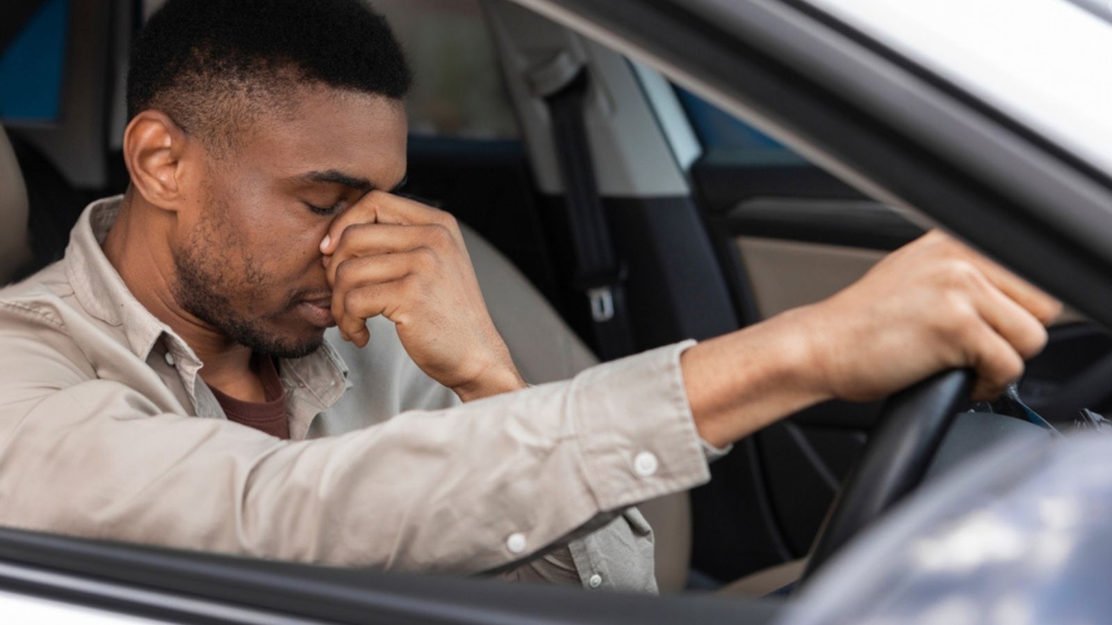Young man sitting inside his car and feeling stressed and upset