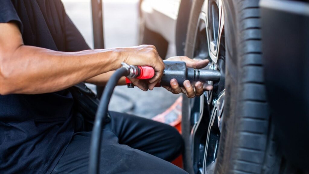 impact air wrench in hand of professional car mechanic working to changing wheel on car