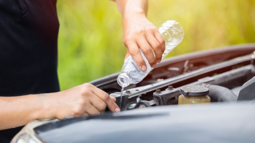 male hand pouring water filling car radiator with concentrated coolant or distilled water for cool engine in summer season