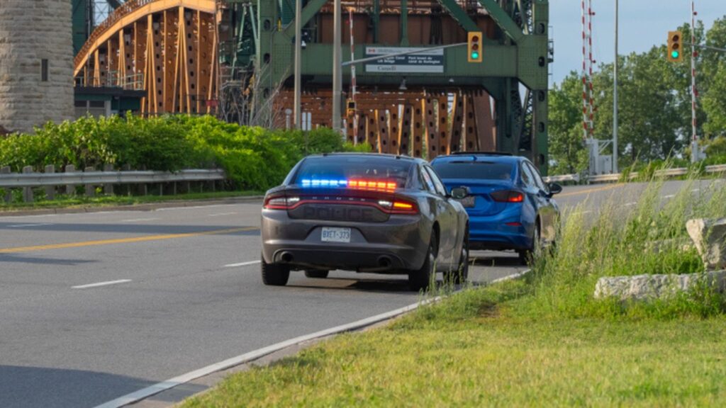 undercover unmarked police OPP vehicle with flashing red and blue lights has pulled over a car on the side of the road