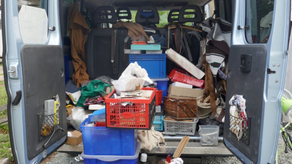 untidy trunk of a delivery van, loaded with old tools, scrap and garbage