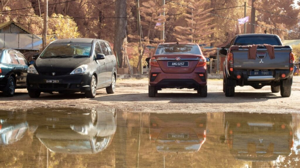 vehicle park beside a reflective pool of stagnant water