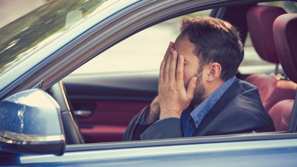 young man sitting inside his car and feeling stressed and upset