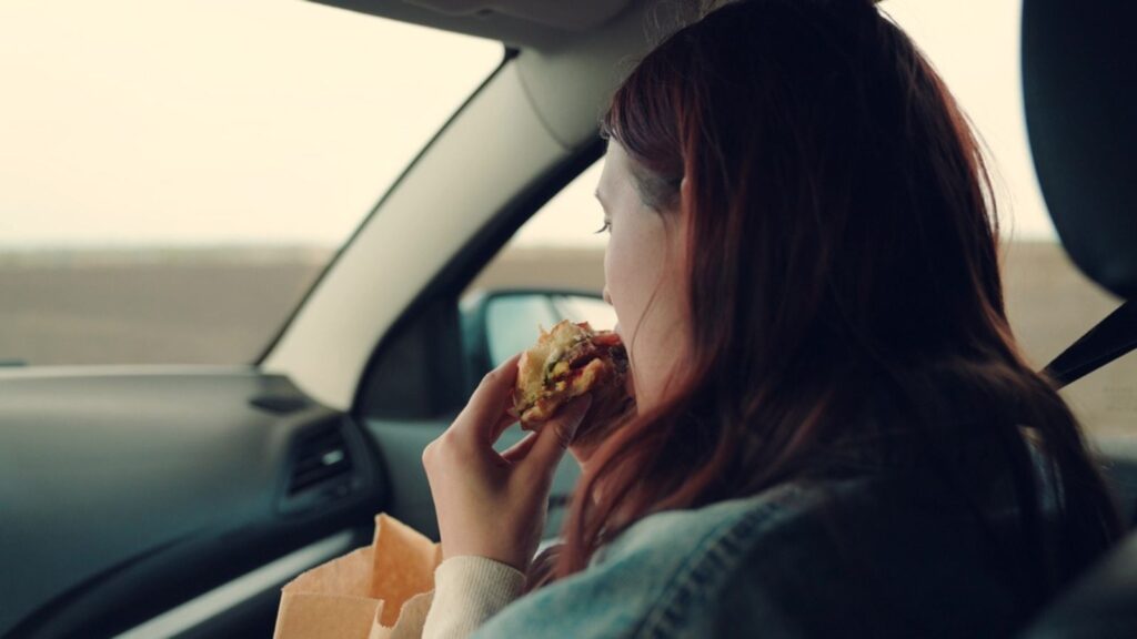 Girl passenger eats burger in car