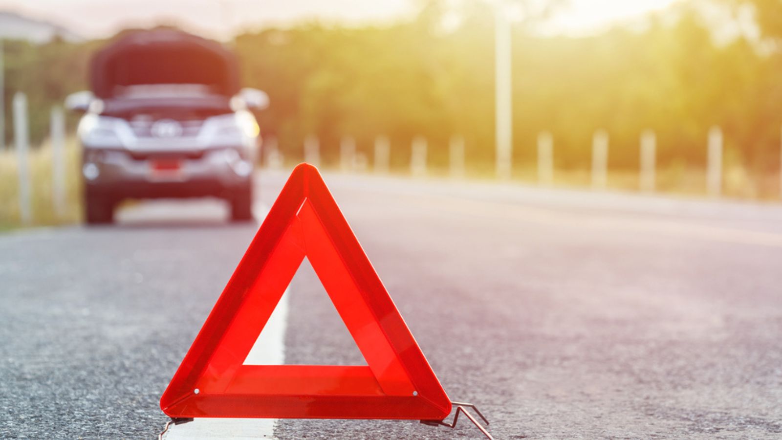 Red emergency stop sign and broken silver SUV car on the road