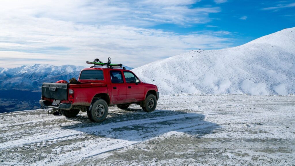 Red pickup truck on road, Beautiful winter road under snow mountains