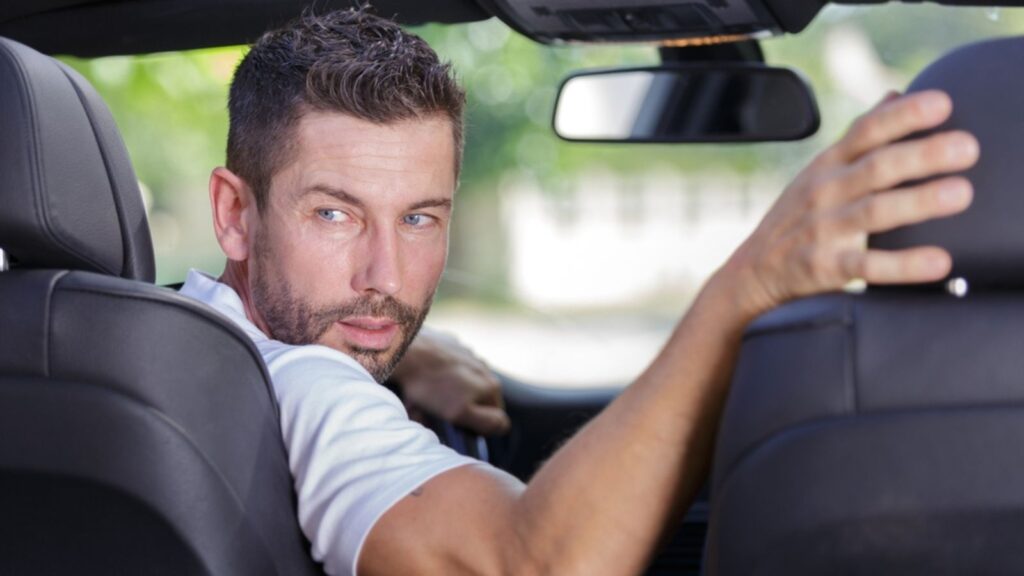 driver turning in his seat to look behind to reverse