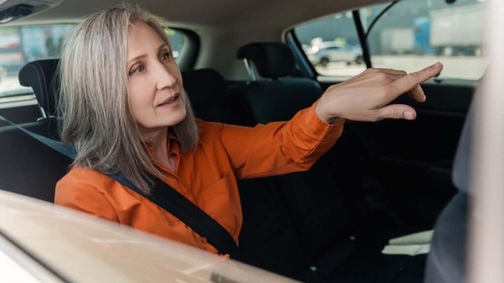 old woman in orange shirt talking to driver